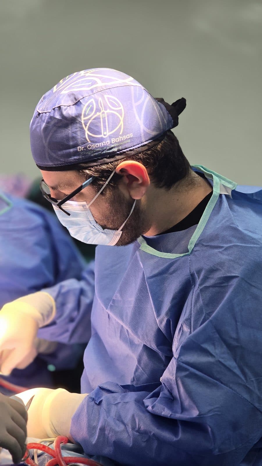El Dr. Bahsas operando en quirófano con gorro y mascarilla