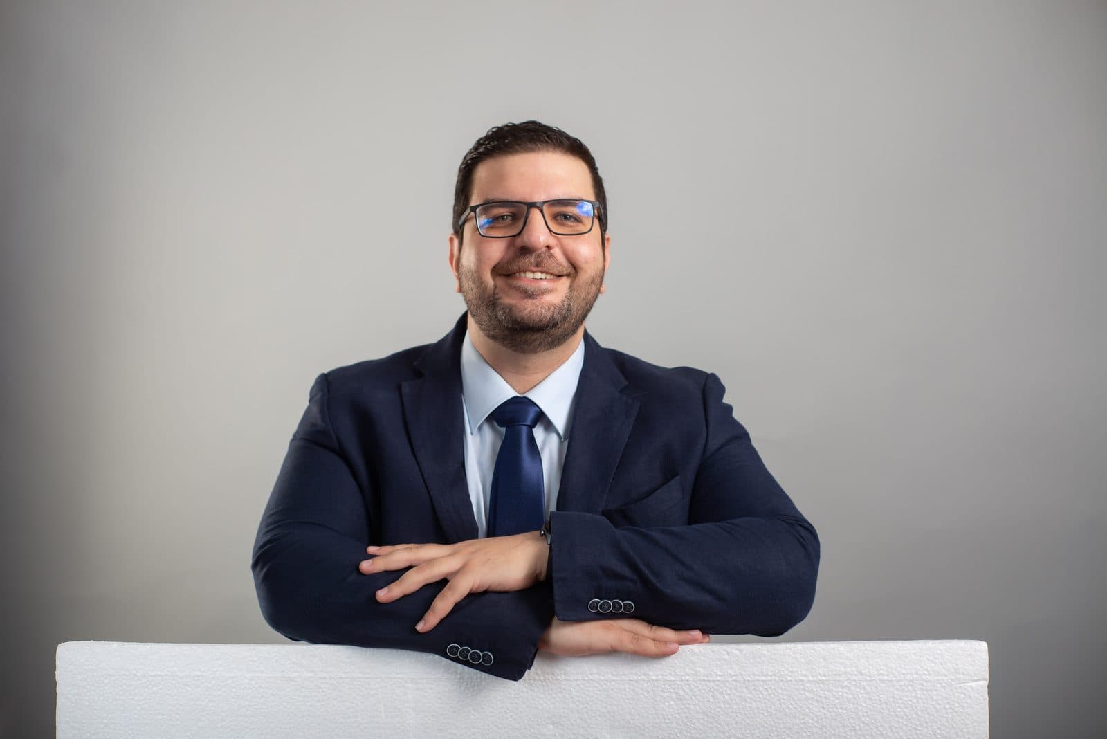 El Dr. Bahsas de traje azul, sonriendo con los brazos apoyados sobre una mesa